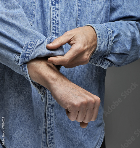 Slika na platnu Man in denim shirt rolling up his sleeves