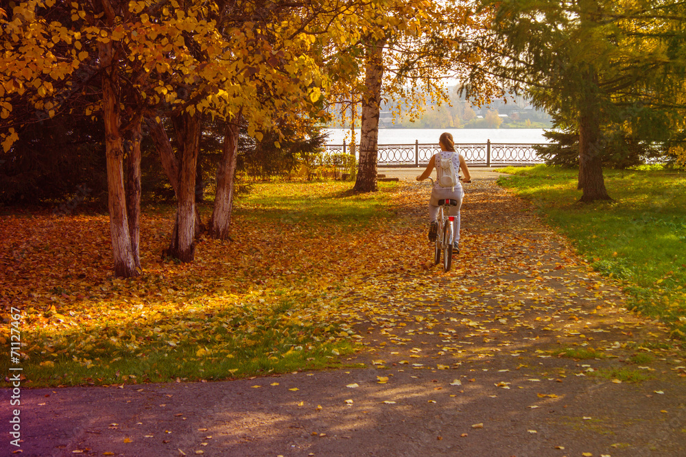 A girl rides a bicycle in the autumn park. A girl rides a bicycle in the autumn park.