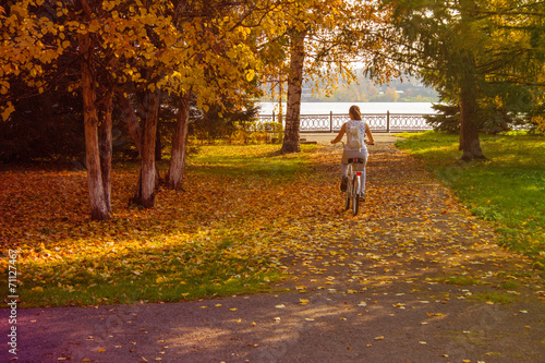 Fototapeta Naklejka Na Ścianę i Meble -  A girl rides a bicycle in the autumn park.