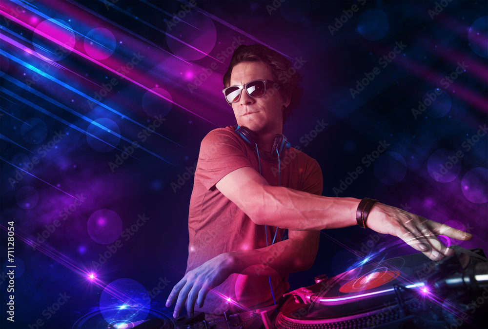 Young DJ playing on turntables with color light effects - obrazy, fototapety, plakaty 