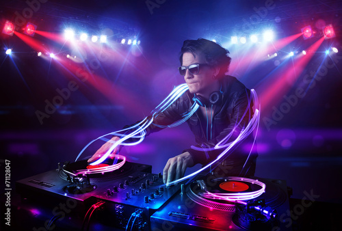 Disc jockey playing music with light beam effects on stage