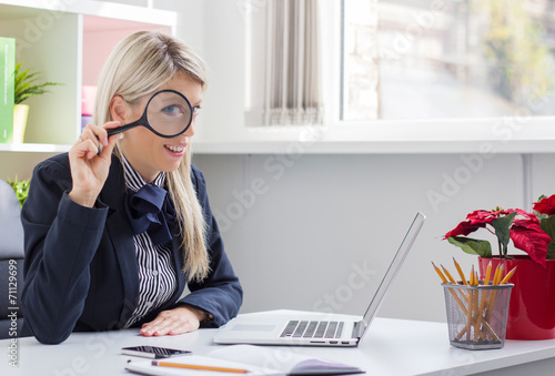 Obraz na plátně Business woman looking through a magnifying glass