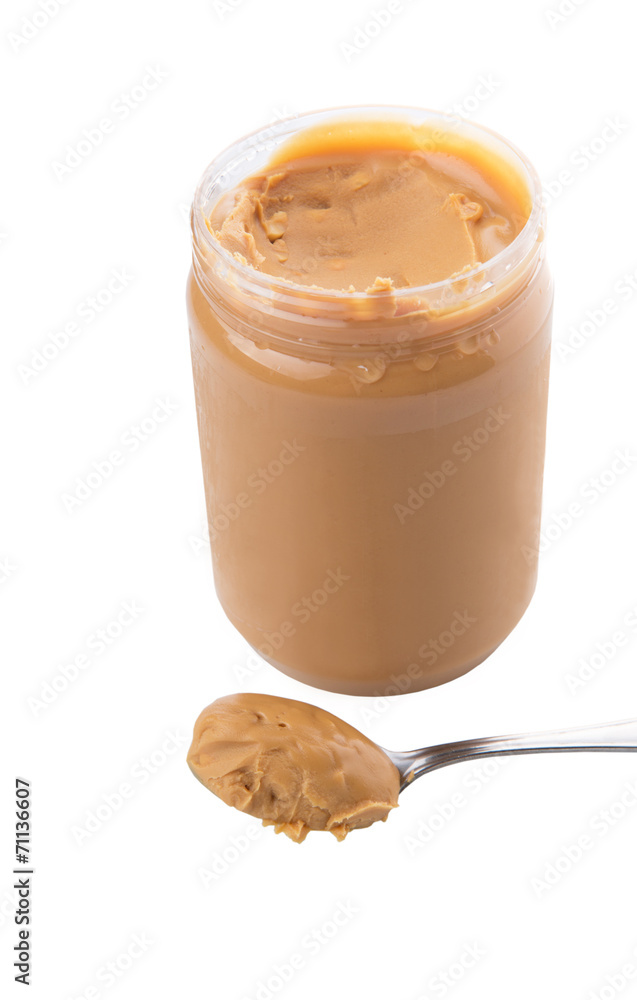 An opened jar of peanut butter with a small spoon An opened jar of peanut butter with a small spoon