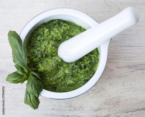 basil pesto in ceramic bowl on wooden background