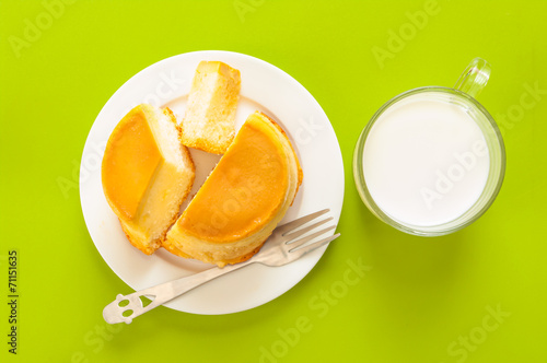 Custard cake and milk on green background.