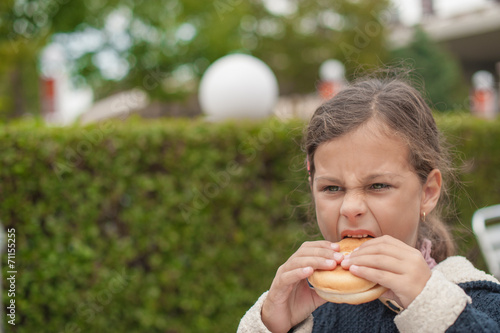 little caucasiangirl eating burger, looking down photo