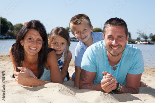 Famille joyeuse allongée sur le sable de la plage des vacances photo