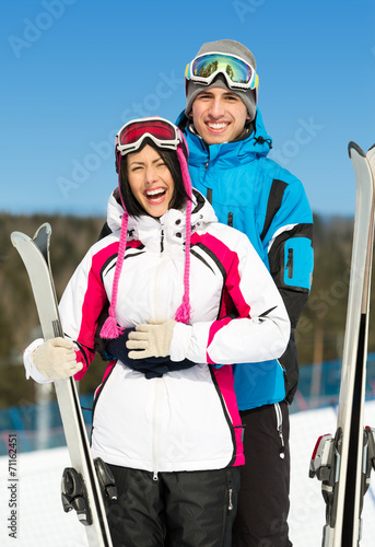 Half-length portrait of two hugging alps skiers with skis