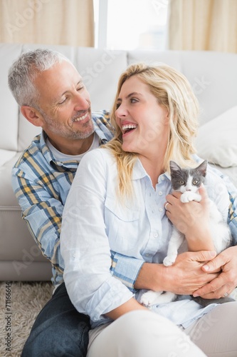 Happy couple with their kitten on the floor