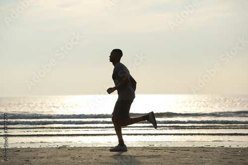 Healthy young man jogging on beach