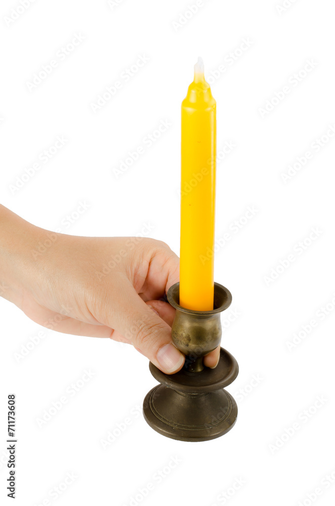 Hand holding candlesticks with yellow candle Hand holding candlesticks with yellow candle