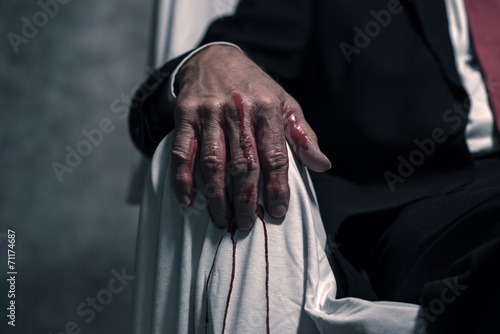 Bloody hand of businessman sitting in white chair.