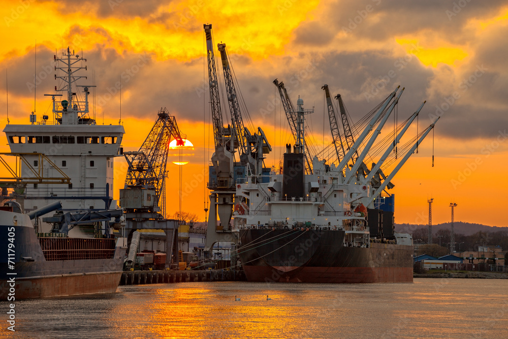 Fototapeta premium Ships and cranes with port warehouse at sunset.