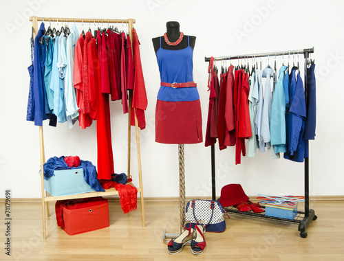 Wardrobe with red and blue clothes on hangers and a mannequin.