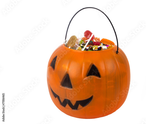 A plastic pumpkin filled with candy isolated on white background