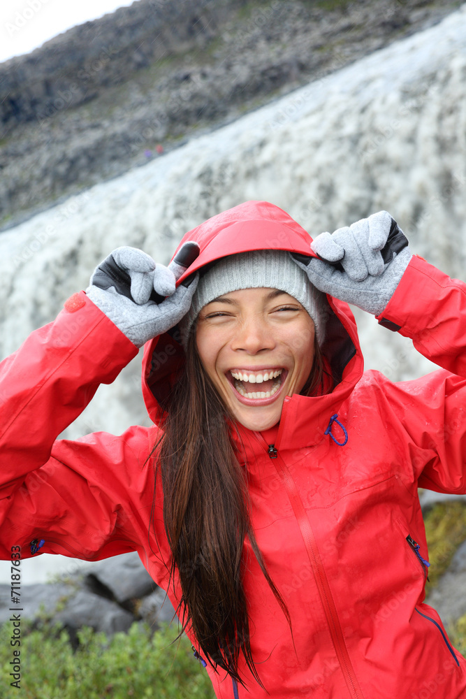 Woman laughing in raincoat by Dettifoss waterfall Woman laughing in raincoat by Dettifoss waterfall