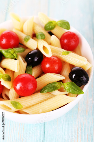 Pasta with tomatoes, olives and basil leaves in bowl