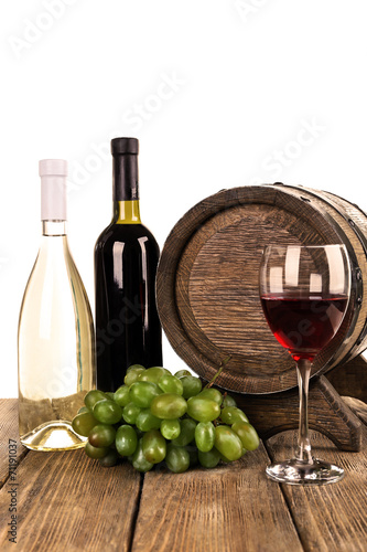 Wine in goblet and in bottles, grapes and wooden barrel