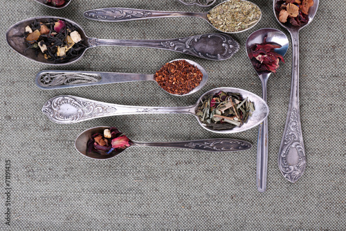 Tea in metal spoons on grey fabric background © Africa Studio