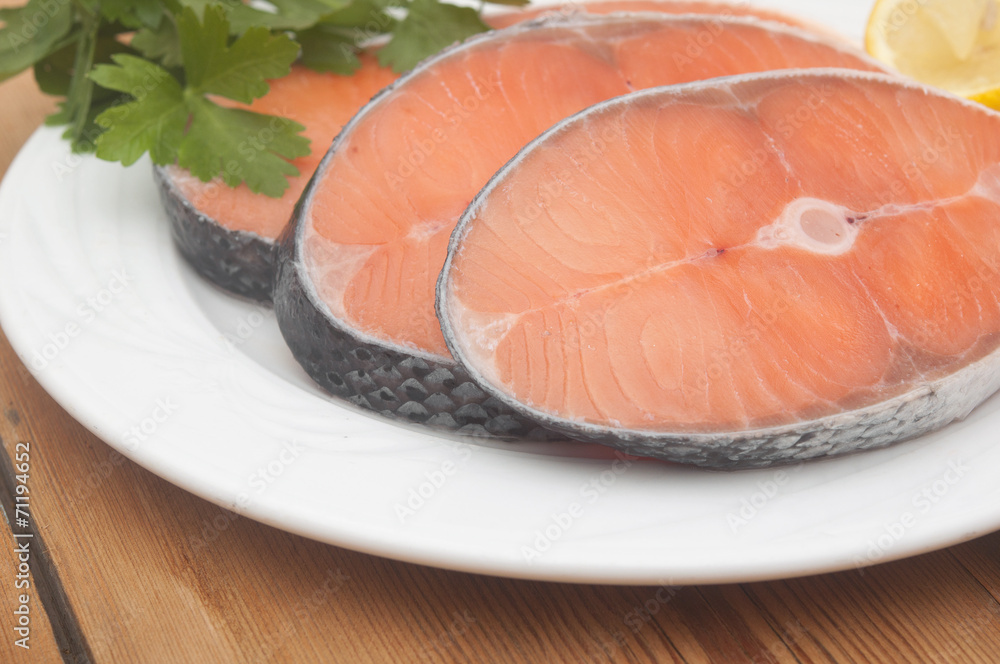 dish for baking with slices of salmon over wooden table