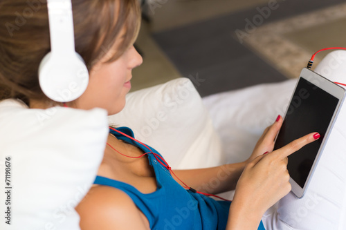 Obraz na płótnie Beautiful girl listening to music with tablet on sofa at home.