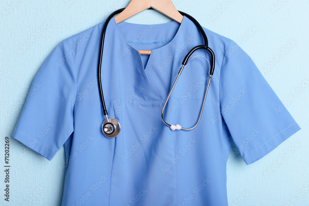 Doctor shirt with stethoscope on hanger on blue background Doctor shirt with stethoscope on hanger on blue background