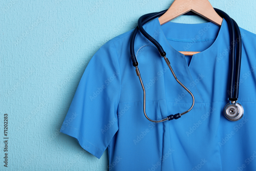Doctor shirt with stethoscope on hanger on blue background Doctor shirt with stethoscope on hanger on blue background