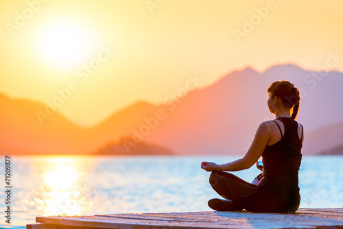 Morning shot of a girl in a lotus position on the pier