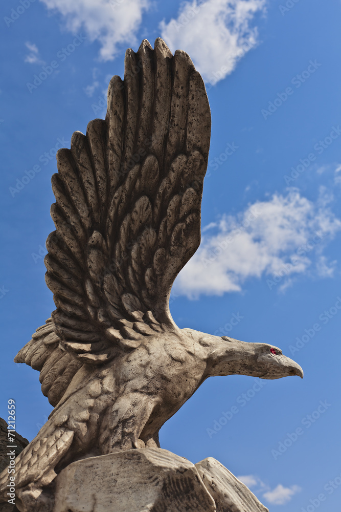 stone statue of a bird eagle on a background of blue sky