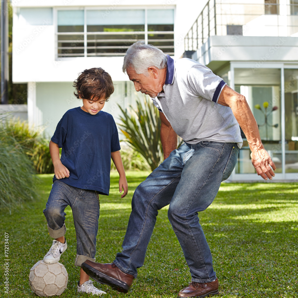 Kind spielt mit Opa Fußball im Garten StockFoto Adobe Stock