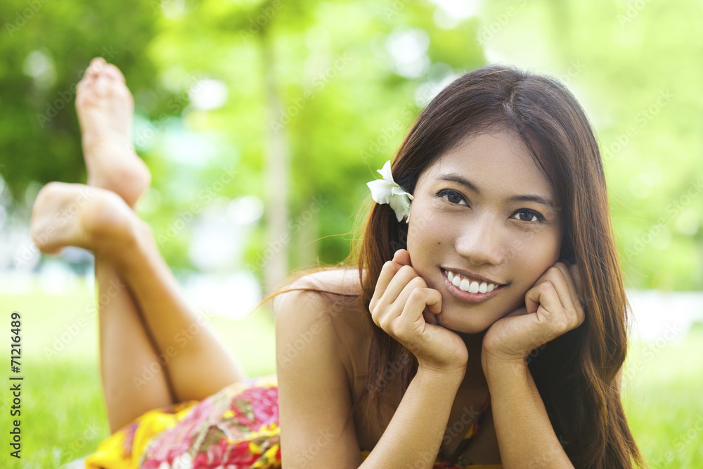 Asian young woman lying on the green grass and smilling Asian young woman lying on the green grass and smilling