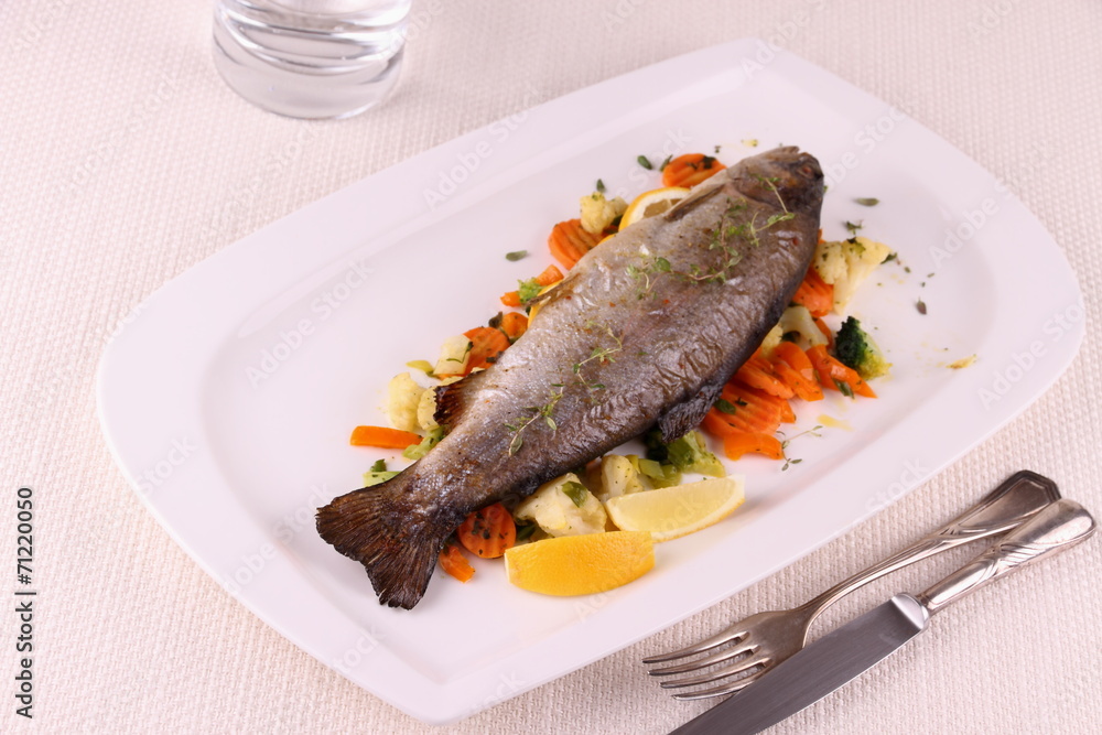 Fried whole trout with vegetables and cutlery Fried whole trout with vegetables and cutlery