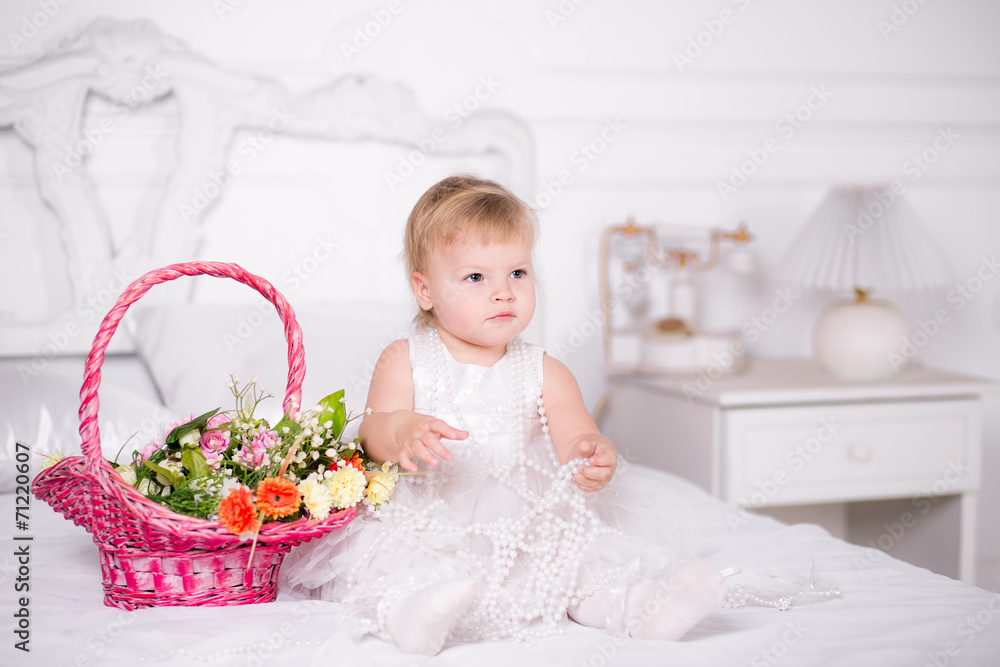 girl in a beautiful dress on a bed with a basket of flowers girl in a beautiful dress on a bed with a basket of flowers