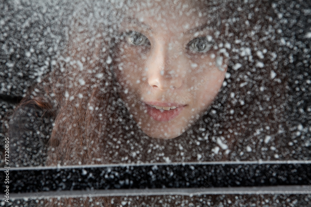 Close up portrait of young girl behind winter snow covered