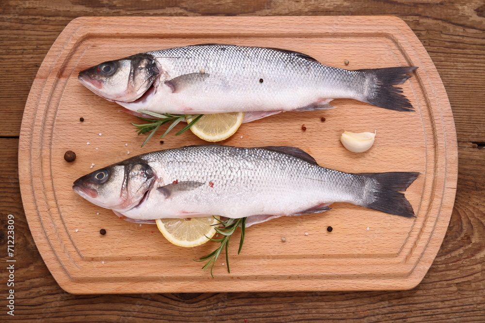 Two fresh moronidae fish on cutting board with ingredients Two fresh moronidae fish on cutting board with ingredients