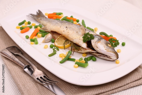Fried whole sea bass with vegetables, lemon