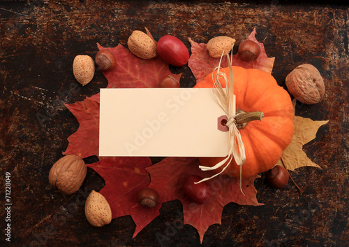 Blank cream tag on top of maple leaves, nuts and pumpkin