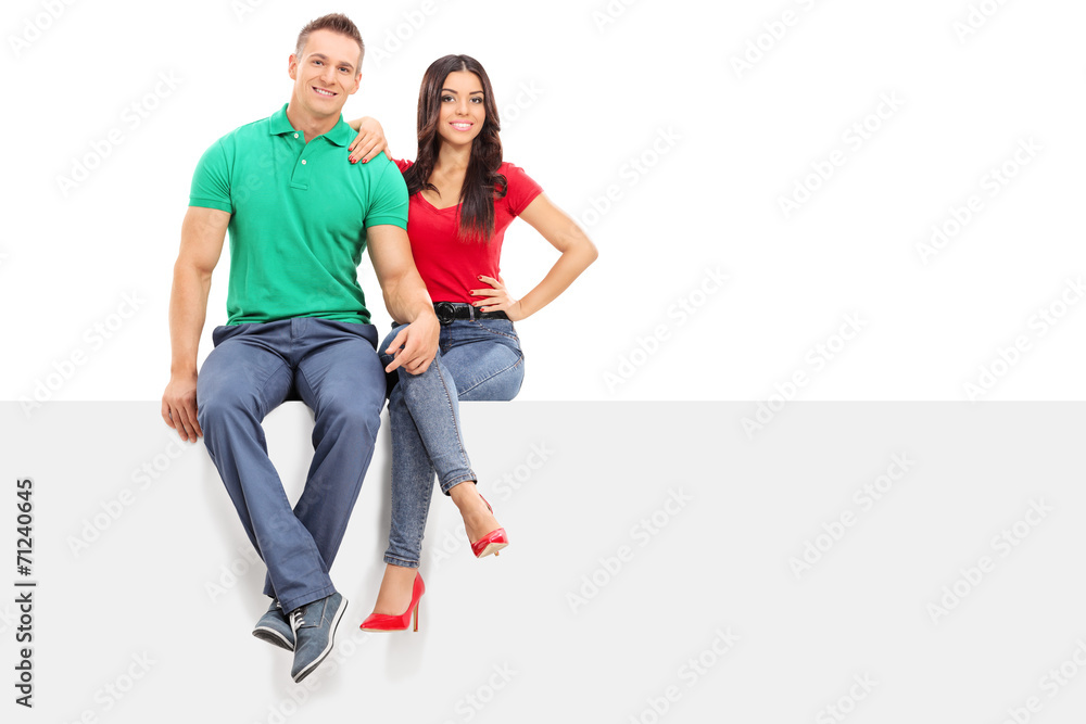 Handsome young couple sitting on a blank panel Handsome young couple sitting on a blank panel