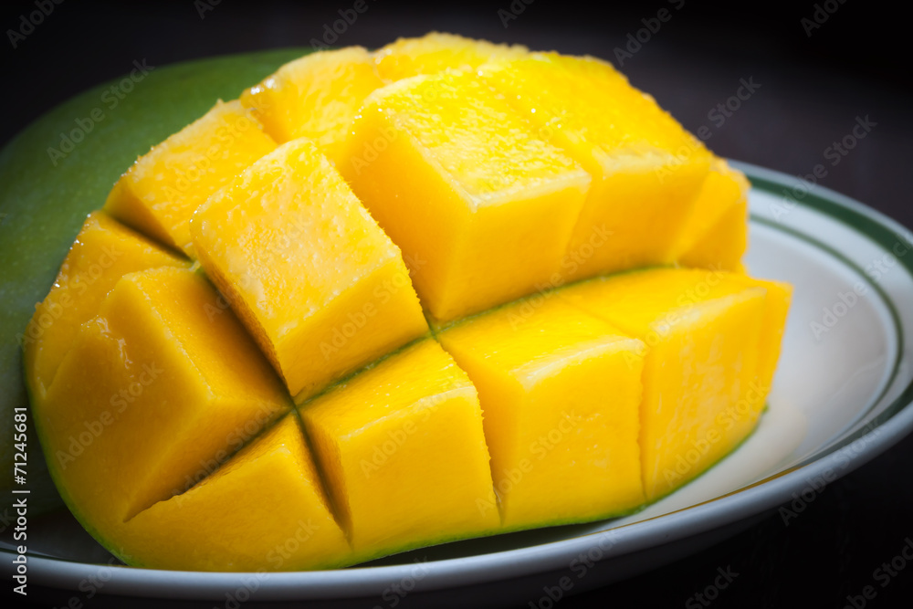 Macro photo of yellow sliced mango on white plate