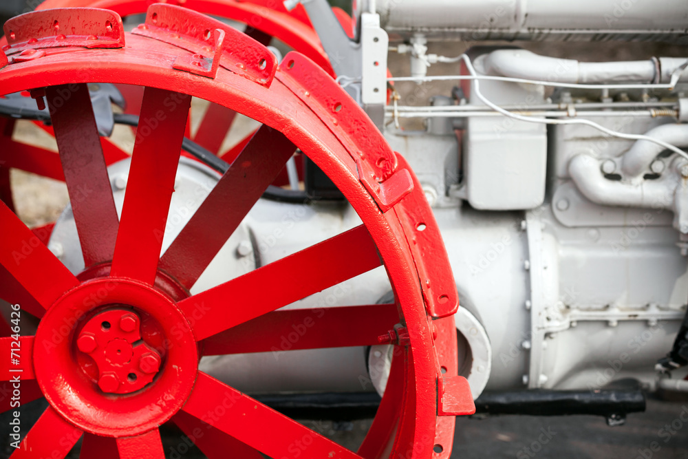 Fragment of old white tractor with red wheel Fragment of old white tractor with red wheel