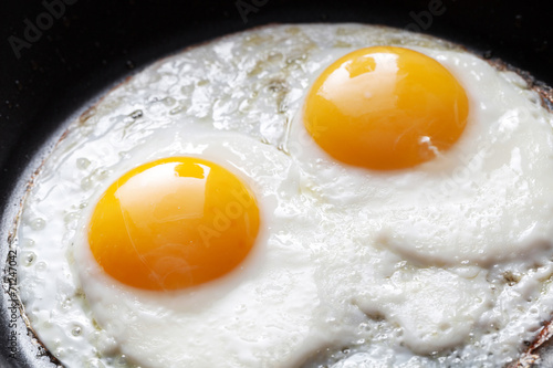 Closeup photo of two scrambled eggs in black frying pan