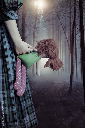 Fotografia Misty haunted forest and a child in a dress with a doll