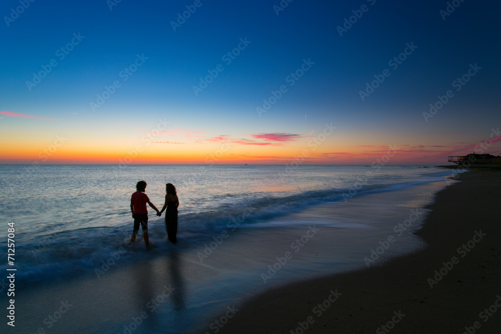 Young couple holding hands on sunrise with water moving