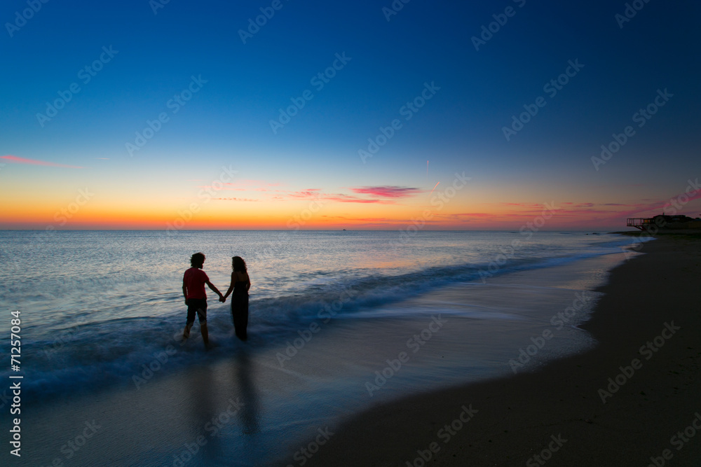 Young couple holding hands on sunrise with water moving Young couple holding hands on sunrise with water moving