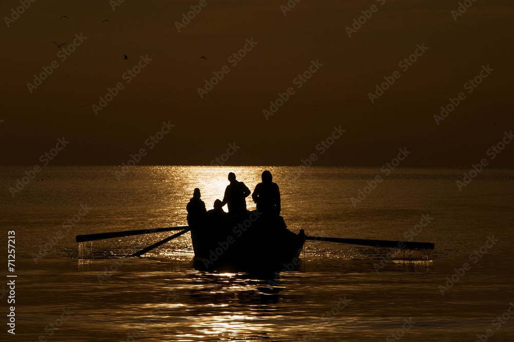 Silhouette of fishermen on the sea at sunrise
