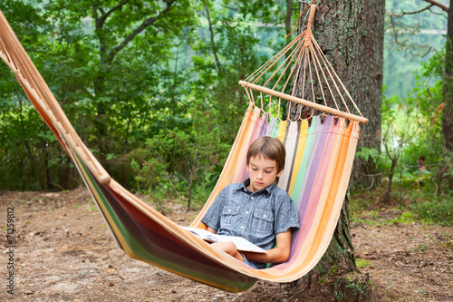 Child reading book in hammock