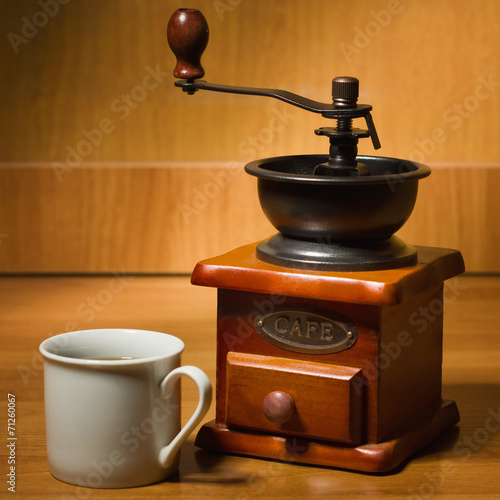 Old coffee grinder and cup on a table