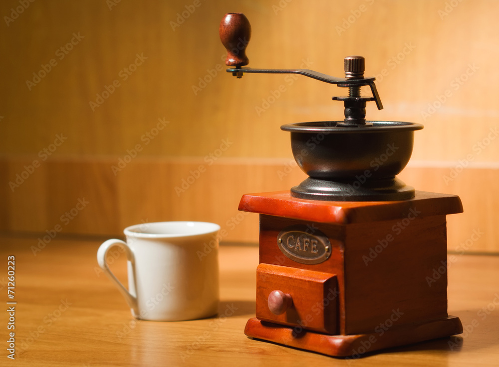 Old coffee grinder and cup on a table Old coffee grinder and cup on a table