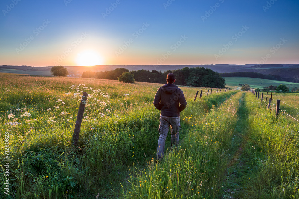 Fototapeta premium Man walking along Track Towards Sunset