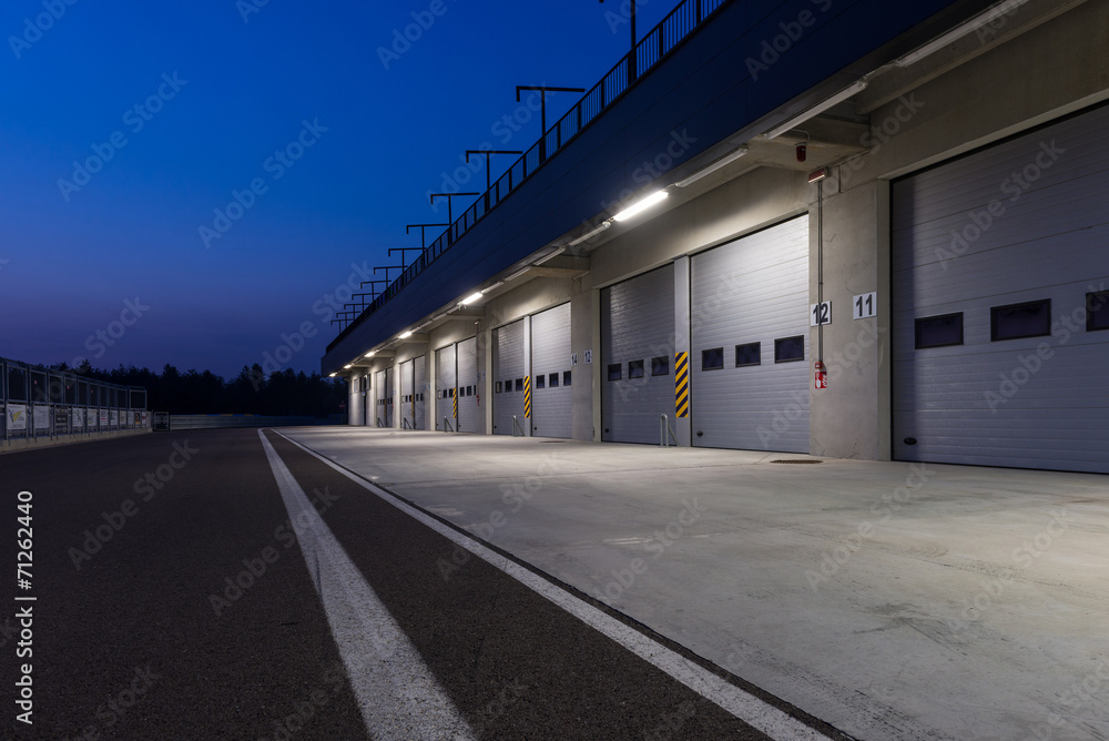 Garages in race circuit. Night time. - obrazy, fototapety, plakaty 